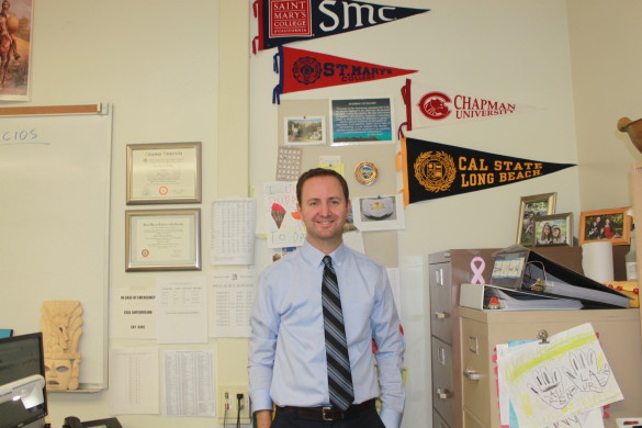 Spanish teacher Jim Diecidue proudly stands in front of his college banners. 