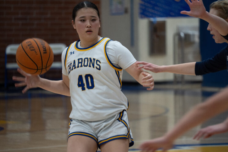 Kailey Nishi Looks for a open teammate while being followed by the defense.